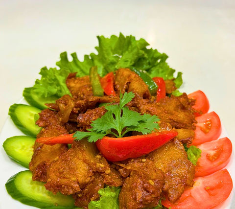 Delicious fried meat dish garnished with fresh vegetables on a white plate.