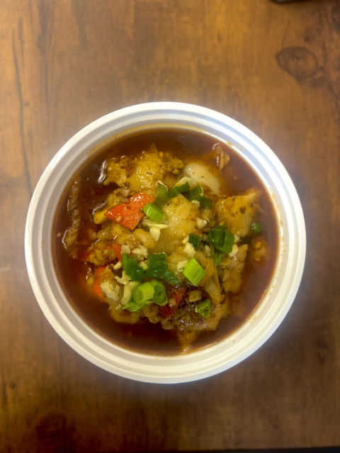 Bowl of soup with vegetables and herbs on a wooden table