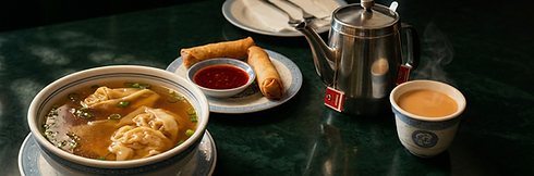 Egg rolls, red dipping sauce, and a metal teapot