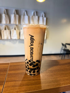 Tall Aura Bobatea drink with boba pearls, on a wooden surface.