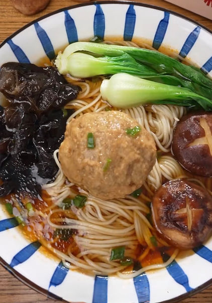 一碗美味的面条，配有蘑菇、蔬菜和肉丸，放在一个碗里。