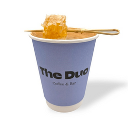 一杯“The Duo Coffee & Bar”咖啡，上面放着蜂蜜，在白色背景下。