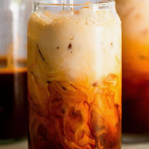 一杯冰泰式奶茶,奶茶颜色分层明显,玻璃杯中,背景模糊