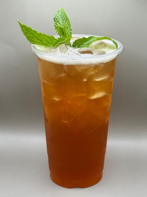 Iced tea in a clear plastic cup garnished with fresh mint leaves.