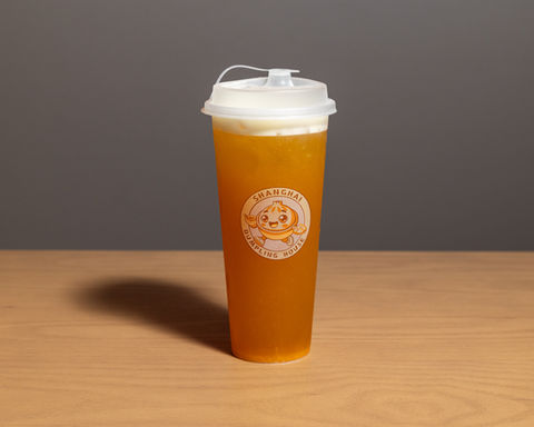 Tall plastic cup of iced tea with creamy white foam