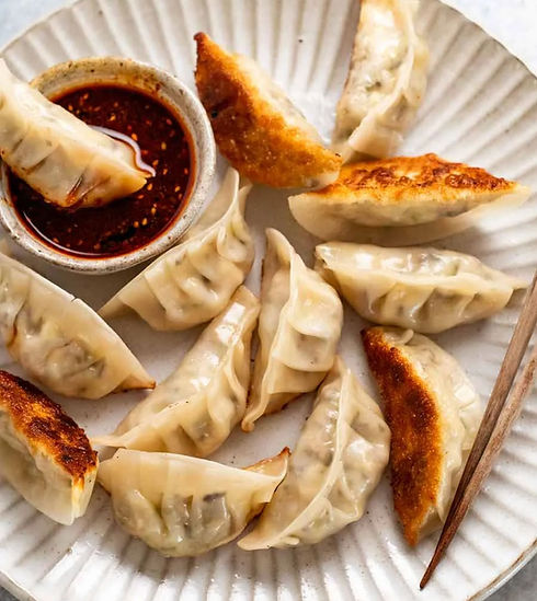Plate of dumplings with dipping sauce, ready for enjoying closeup view.