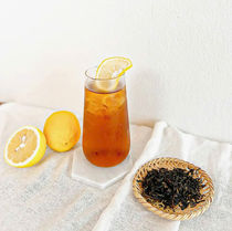 一杯柠檬茶,柠檬切片和半个柠檬,旁边是茶叶和背景。