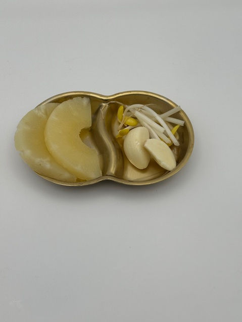 Canned pineapple slices with bean sprouts and garlic in a gold dish