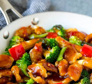 Chicken stir-fry with broccoli, red peppers, and baby corn served in a pan.