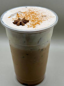 Iced drink in clear cup with foam, star anise, and cinnamon. 