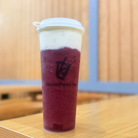 Ocean Cheese Tea紫色奶盖饮品，顶部白色奶盖，置于木桌。