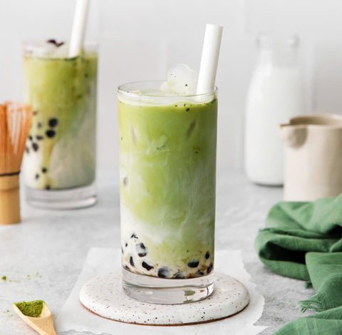 抹茶珍珠奶茶,两杯冰镇奶茶,配有吸管和背景中的牛奶。
