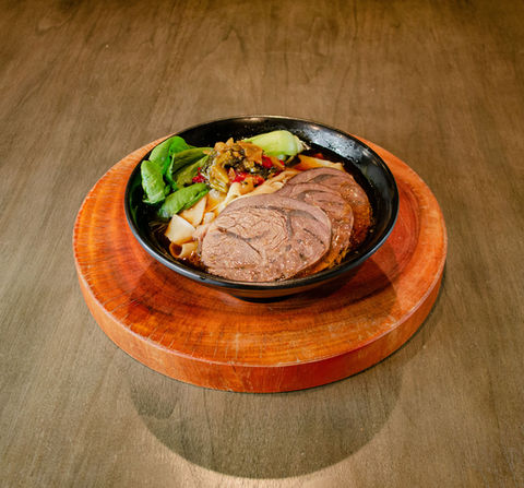 红烧牛肉面搭配青菜在木桌上的美味佳肴