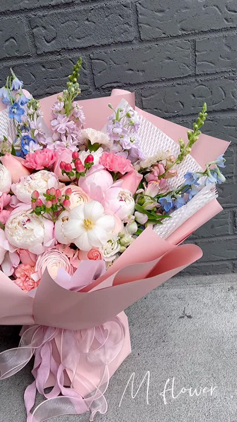 Bouquet of pink and white peonies with blue flowers, pink wrap