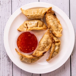 Plate of dumplings with dipping sauce, ready to be enjoyed.