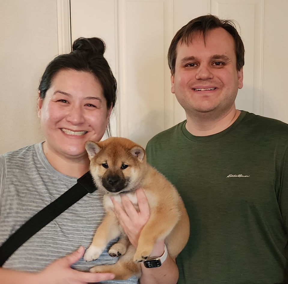 Happy couple holding their adorable new Shiba Inu puppy