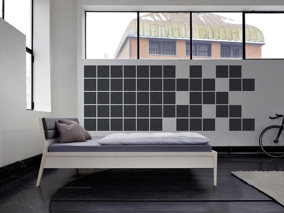 Modern bed in a room with square wall decor and a bicycle.