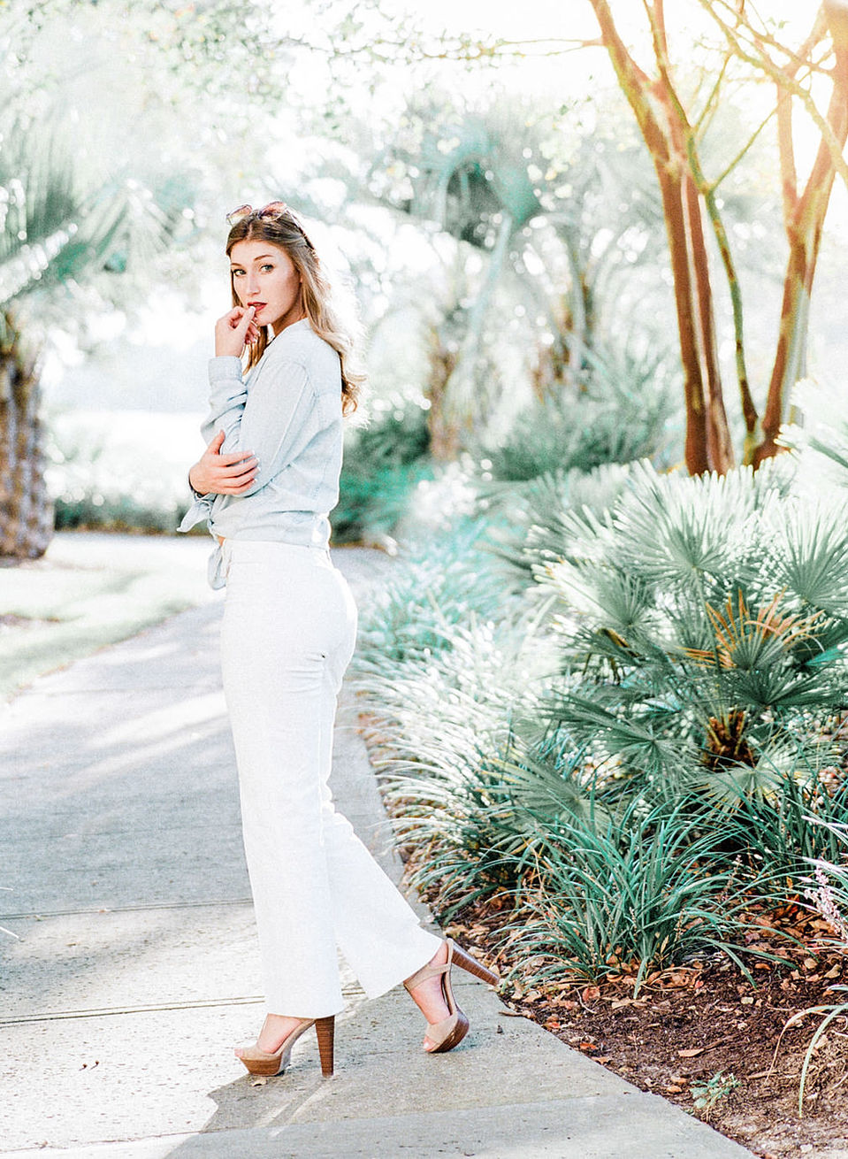 Confident senior portrait with palm trees and white trousers