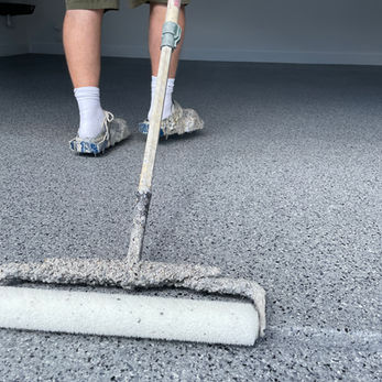 Professional application of a high-gloss polyaspartic topcoat over epoxy flake flooring in an Austin, TX garage for UV-stable durability.