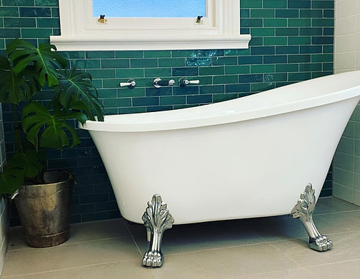 Luxurious bathroom showcasing hand-cut emerald subway tiles and a freestanding claw foot bath. Rich colour and timeless materials create a restorative retreat designed for relaxation, comfort and everyday indulgence.