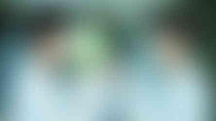 A young man looks at his reflection in a mirror, touching it with both hands, symbolizing self-reflection or identity exploration.