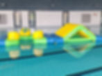Aufgeblasenes Spielgerät mit Rutsche schwimmt im Hallenbad auf dem Wasser.