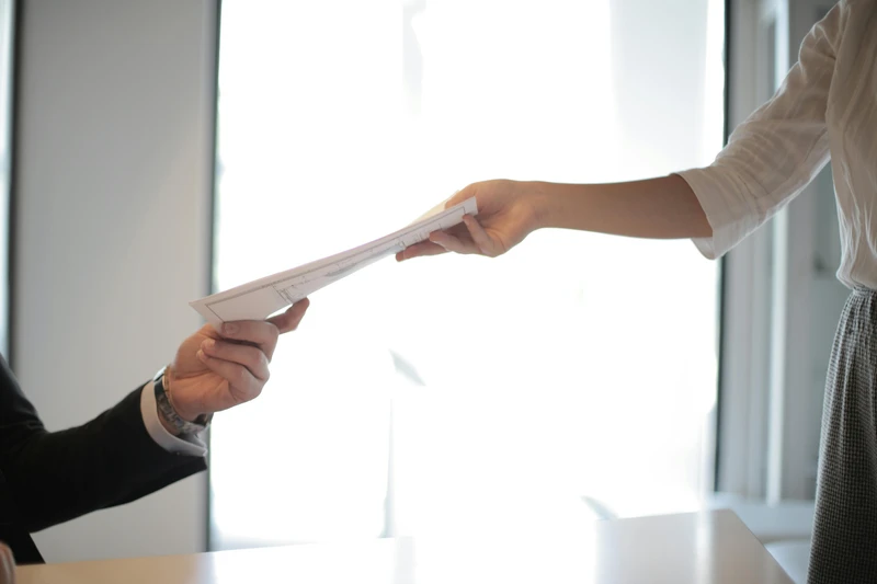 A woman is handing a contract to a man.