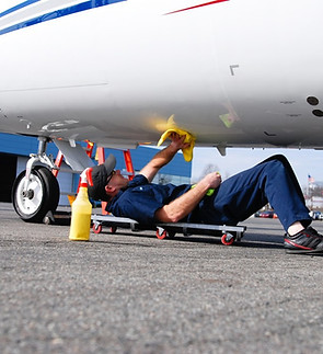 A man cleaning the underside of a private jet. removing all contaminant buildup.