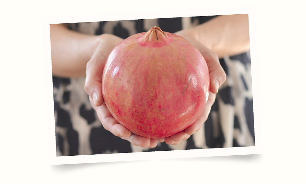person holding a red pomegranate in the palms of their hands
