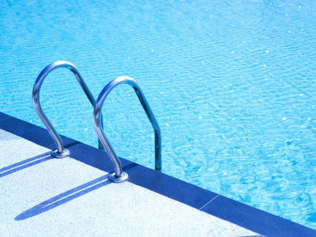 Metal pool ladder beside clear blue water