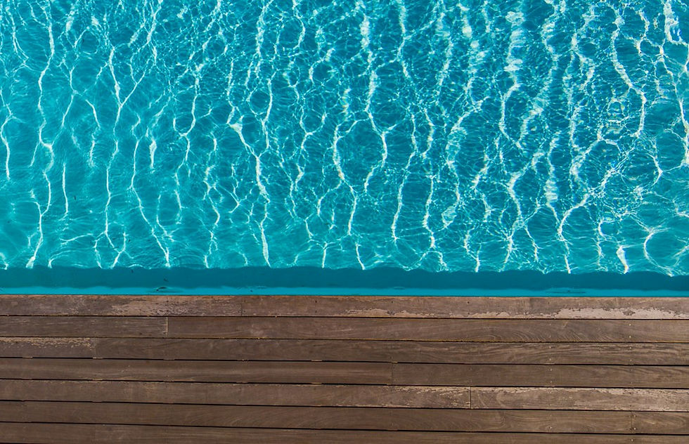 Clear blue pool water beside wooden deck