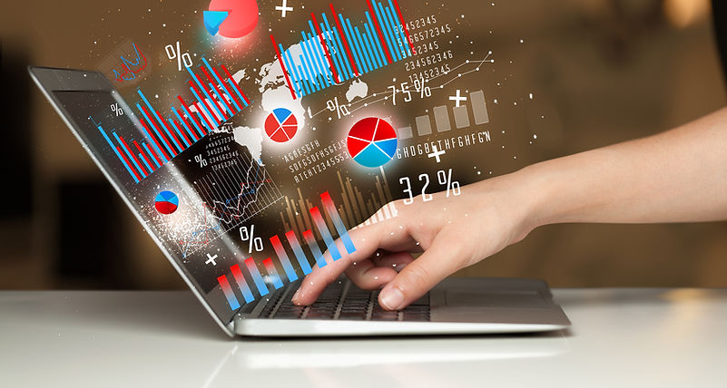 Hand typing on a laptop with graphs coming out of the screen