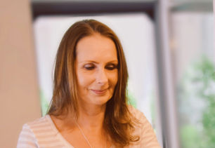 Frau arbeitet am Laptop, lächelt leicht, helle Kleidung, gestreiftes Shirt, Start Fluoriya