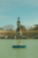 The Retiro Park lagoon with a person in a row boat and the Monument to Alfonso XII in the background