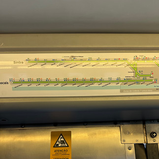 Wall-mounted subway map showing a single train line with labeled stations and a caution sign below. The design appears to guide passengers through a specific metro or commuter rail route.