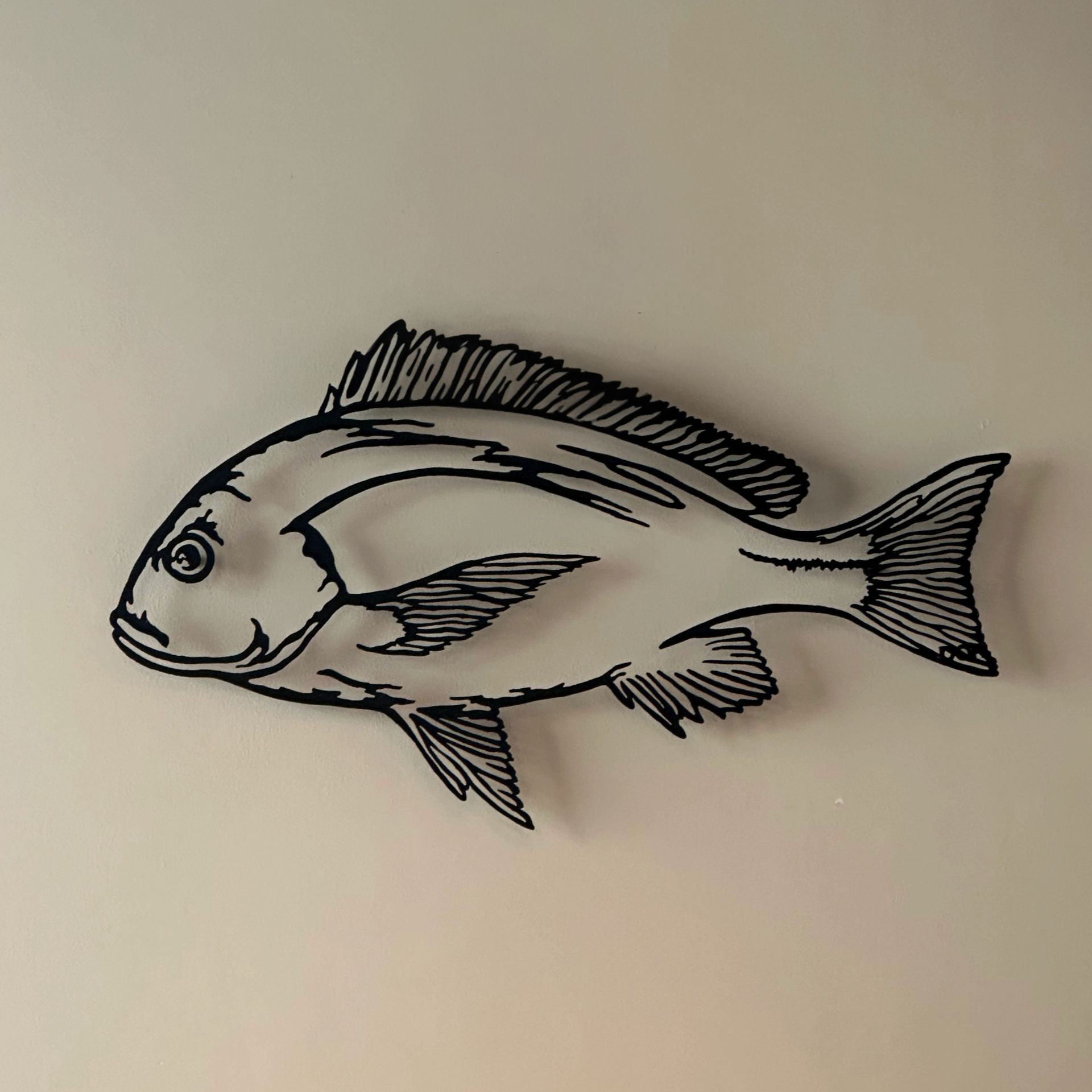 Wall art at Restaurante Albalá, black metal fish sculpture mounted on a beige wall