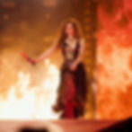 Shakira performing on stage in a metallic outfit surrounded by flames, from a concert in MedellÃn, Colombia.