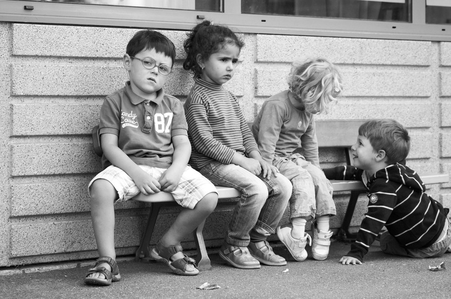 4 enfants sur un banc dans la cour de récréation