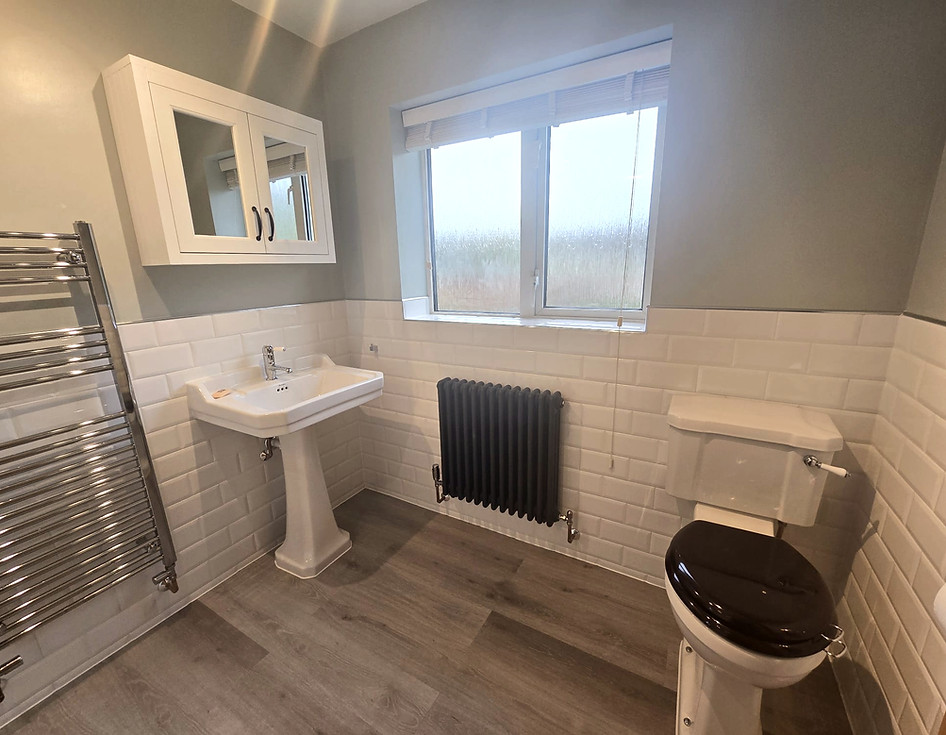 Modern bathroom renovation with white sink, toilet, towel rail