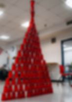 Tall pyramid of stacked red plastic cups in a classroom setting with white walls, a red chair, and an American flag visible.