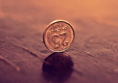 A coin balancing on a table surface