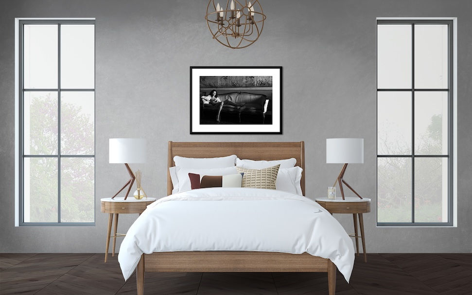 Lifestyle boudoir photo displayed above a bed in a modern, minimal bedroom with neutral tones and natural light.