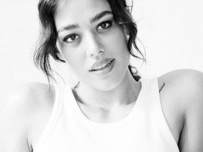 dark haired woman in white tank top, photo cropped chest up