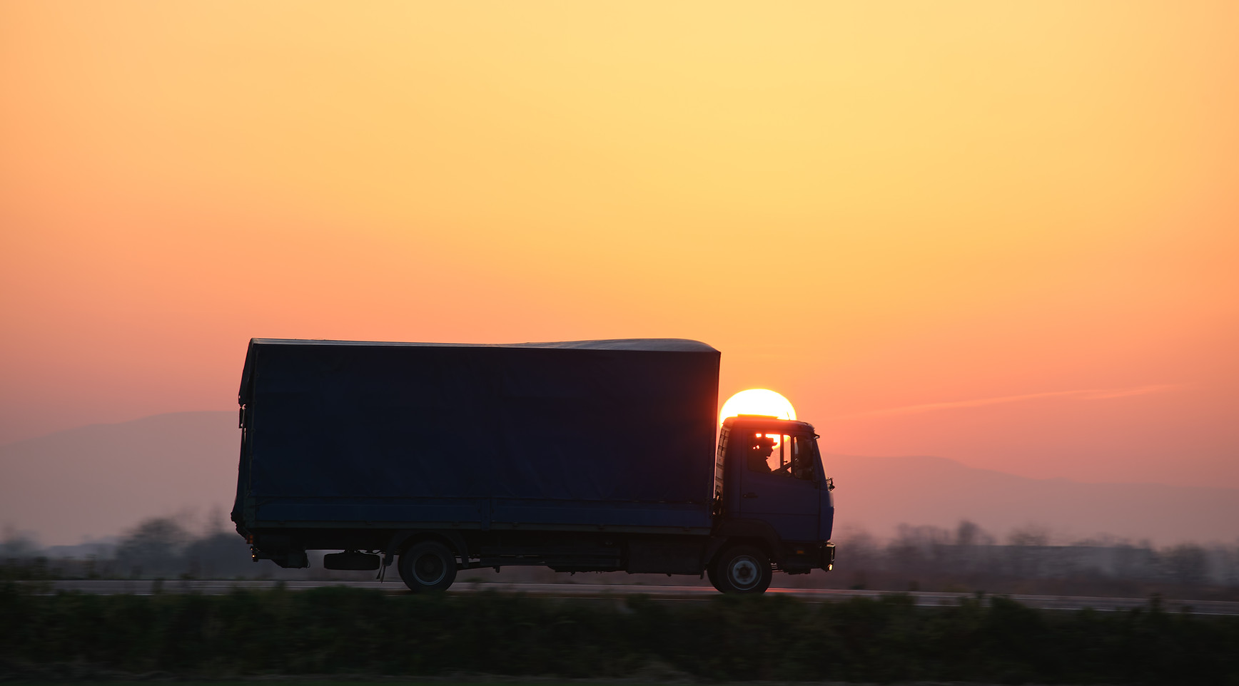 cargo-truck-driving-on-highway-hauling-goods-in-ev-2022-03-29-23-53-48-utc.jpg
