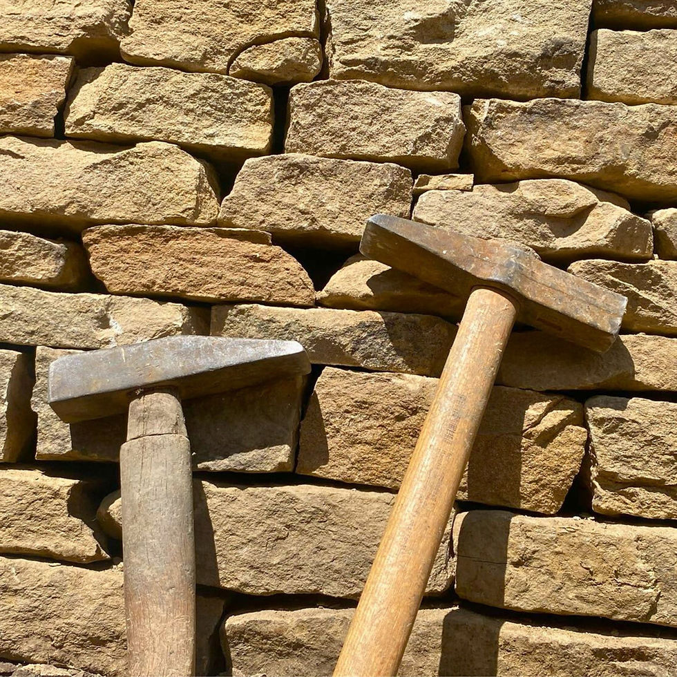 Masonry hammers leaning against a dry stone wall