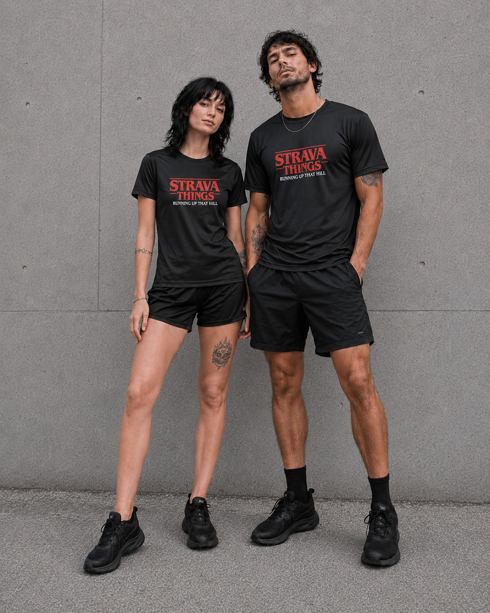 Male and female models wearing matching Strava Things black technical running shirts with red and white graphic print, standi