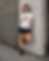 Thumbnail: Model wearing the white Street Runner technical running shirt with black running shorts in an urban street setting.