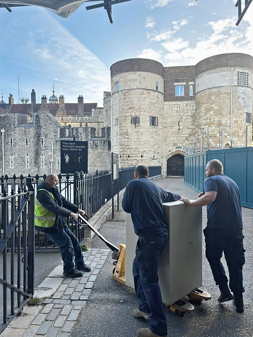 Workers moving object, front of Tower of London, blue sky in background