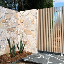 This beautiful mix of high quality materials came together perfectly. Aluminum batten gate, stone cladding, blue stone crazy paving and low maintenance greenery. 