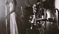 Man Plucking a Double Bass in a Nightclub and a Female SingerStanding